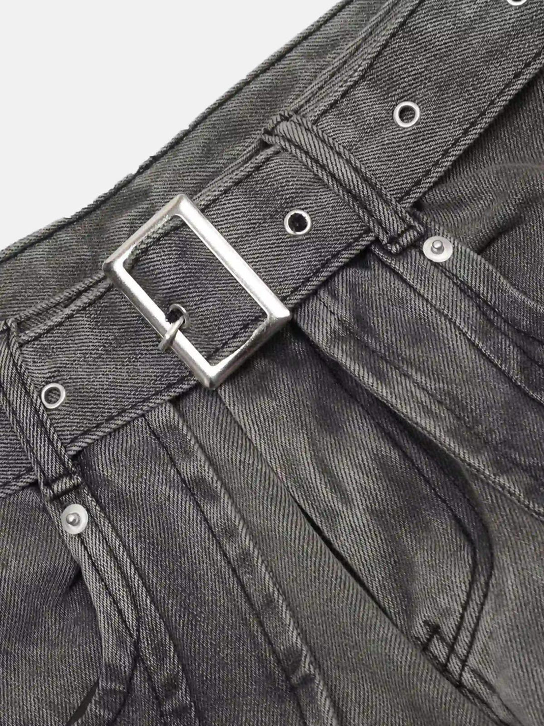 Detailed view of TALISHKO's distressed punk jeans, highlighting the metal belt and stitching.