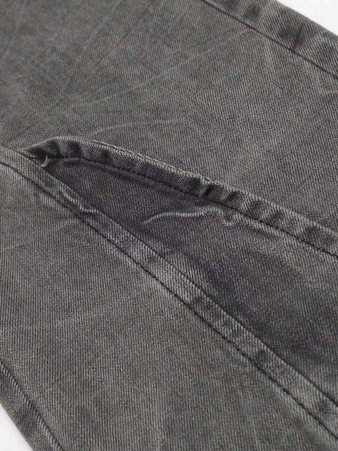 Intricate look at TALISHKO's distressed punk jeans, focusing on detailed stitching and texture.