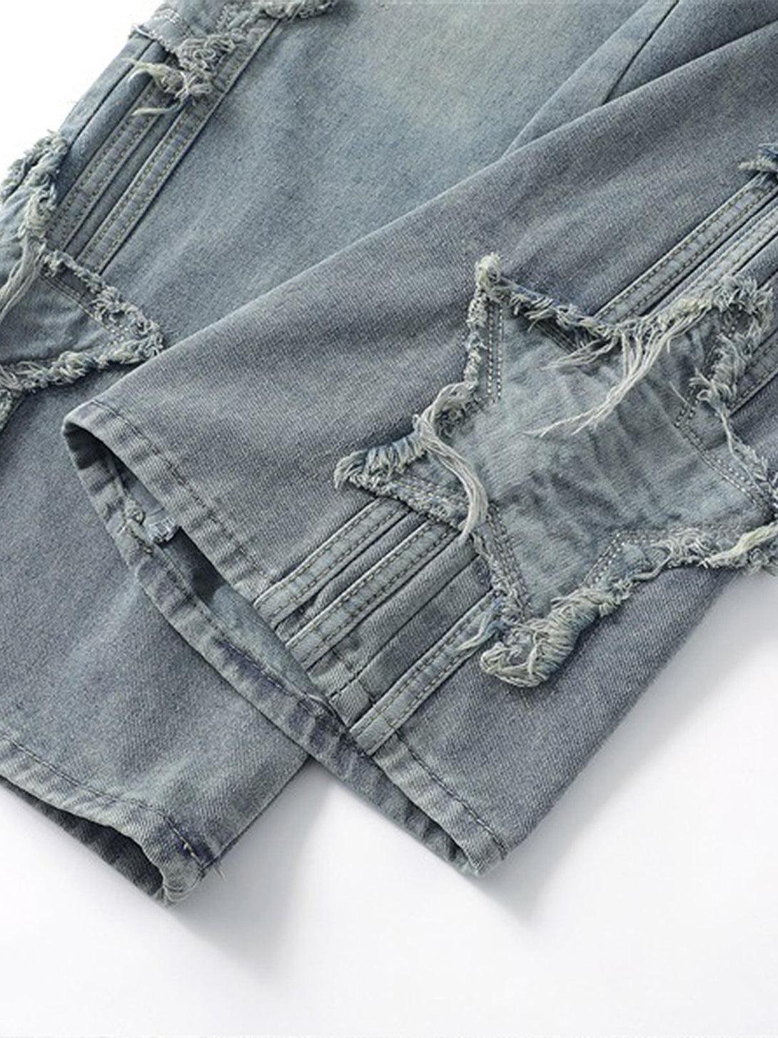 Intricate look at TALISHKO distressed jeans, highlighting star-shaped raw edge details.