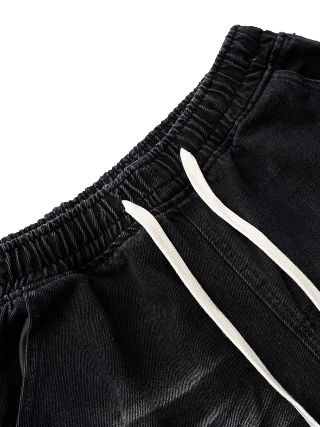 A close-up of TALISHKO's distressed barrel jeans, highlighting the drawstring waistband detail.