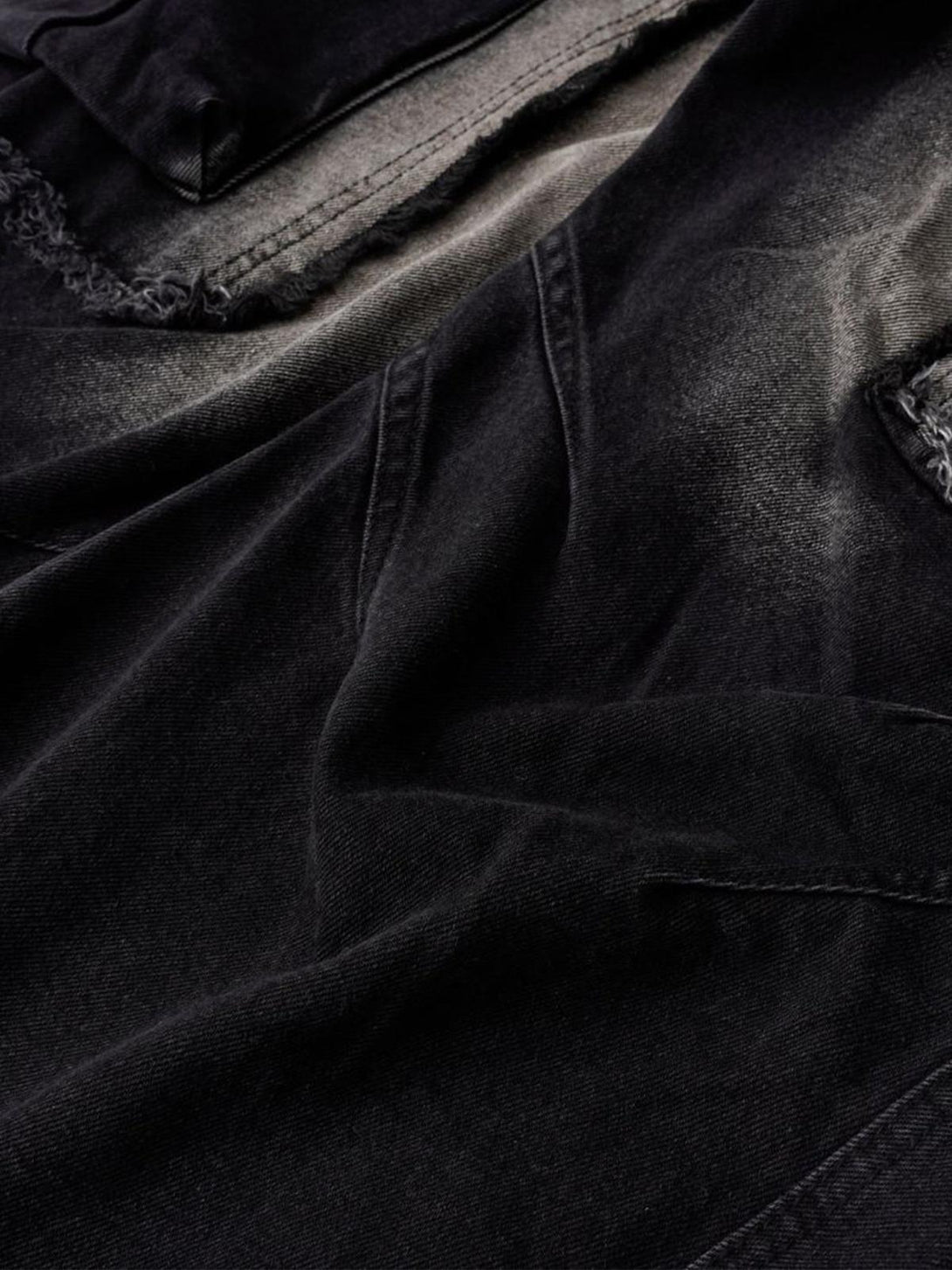 Detailed fabric and stitching of TALISHKO's distressed raw edge cargo jeans.