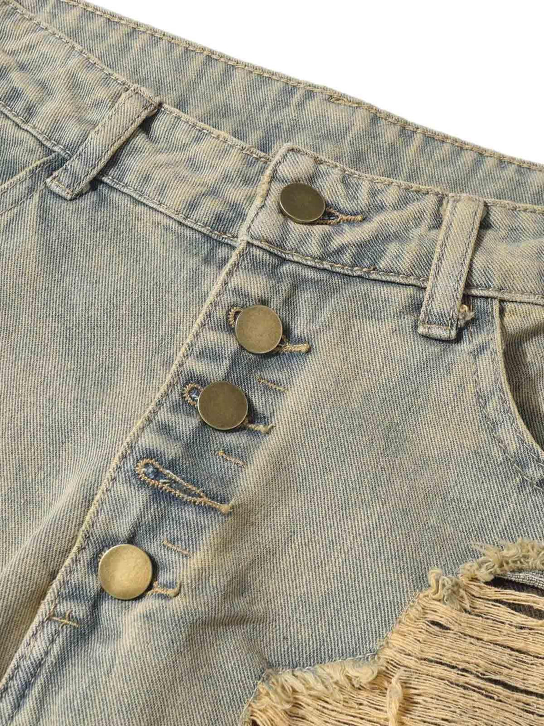 Focusing on the button details and distressed raw edge of TALISHKO jeans for unique texture.