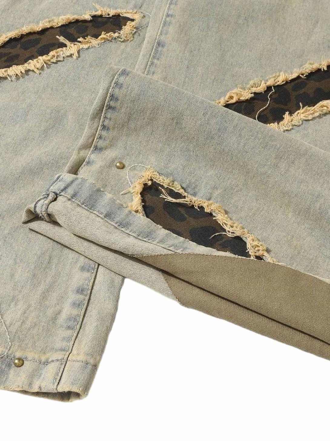 Close-up of TALISHKO distressed jeans with raw edge patches revealing a unique textured design.