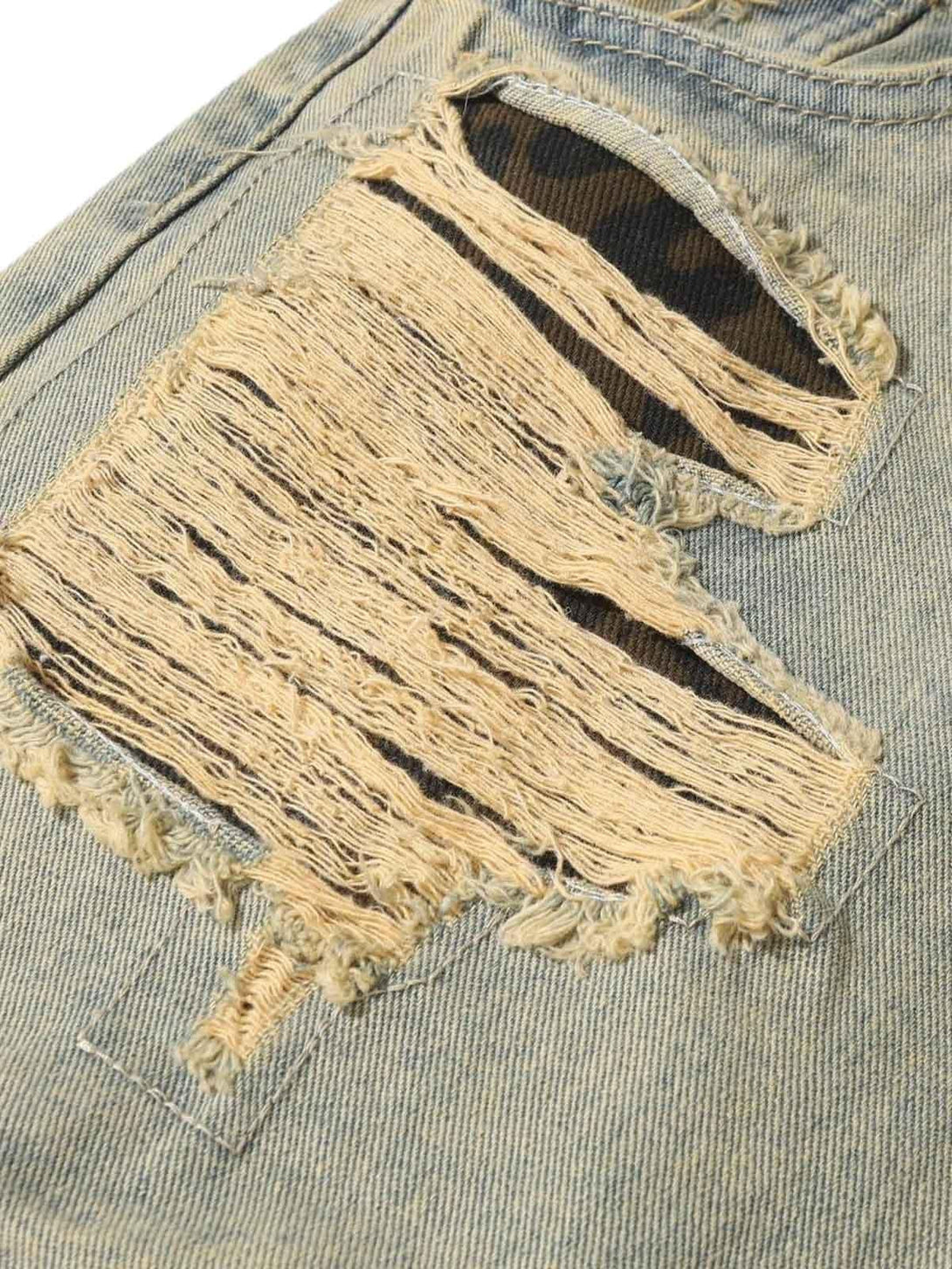 A detailed look at distressed raw edge patch jeans by TALISHKO, showcasing unique texture.