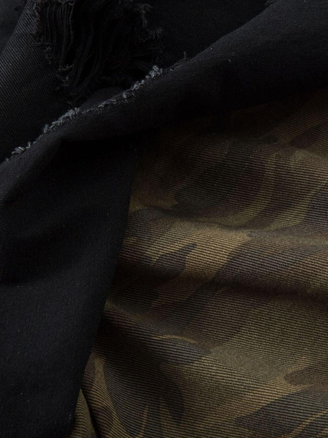 A detailed view of TALISHKO shorts displaying camo lining and distressed fabric texture.