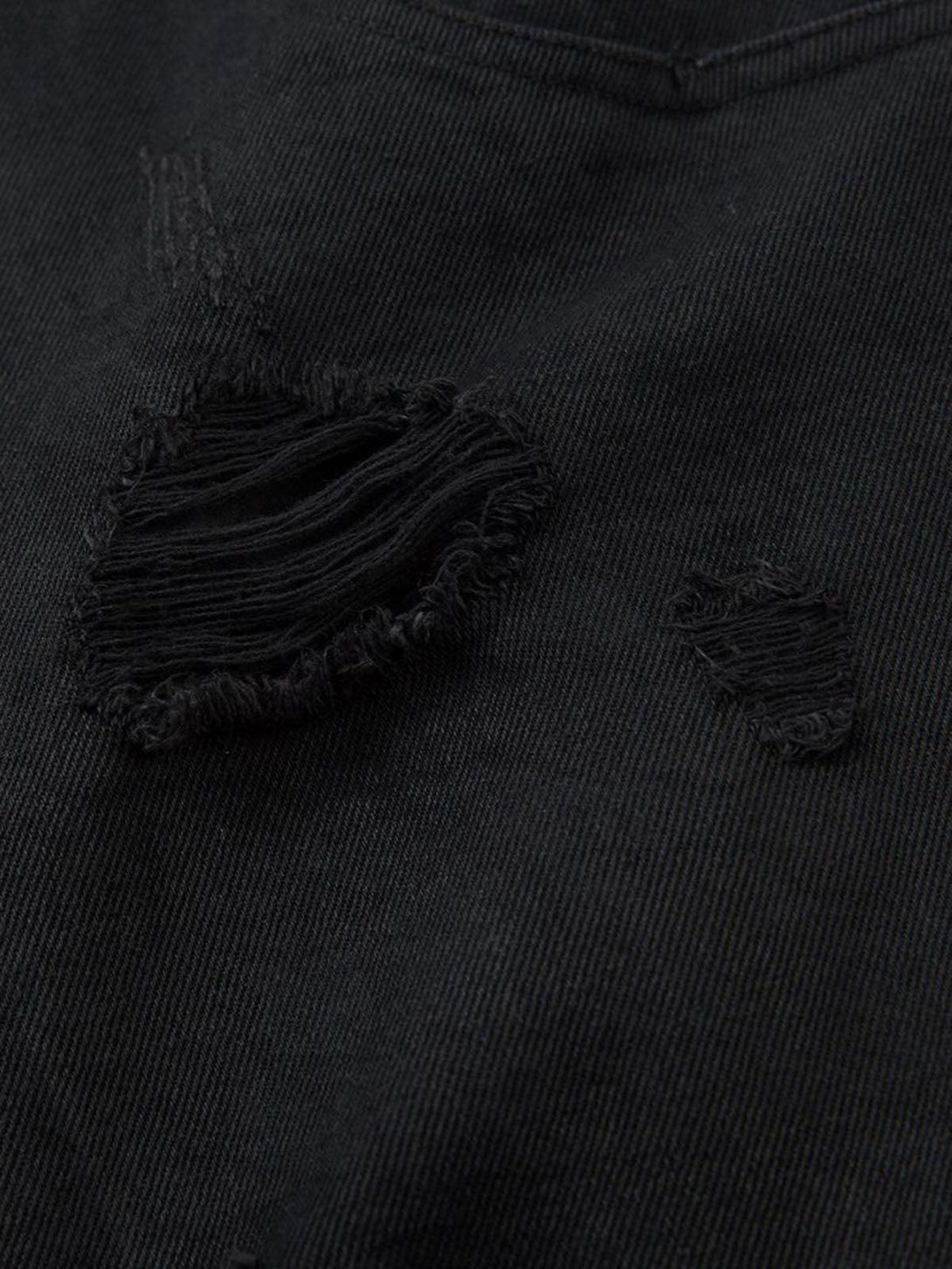 Zoomed-in texture of TALISHKO black denim shorts highlighting distressed rips and fabric details.