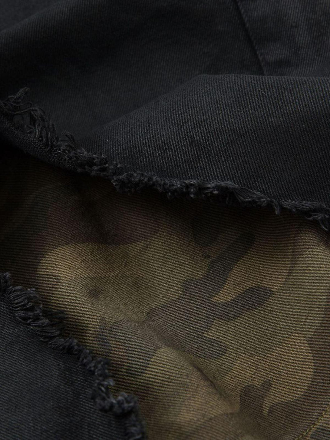 Texture and pattern showcased in TALISHKO black denim shorts with distressed rips and camo lining.