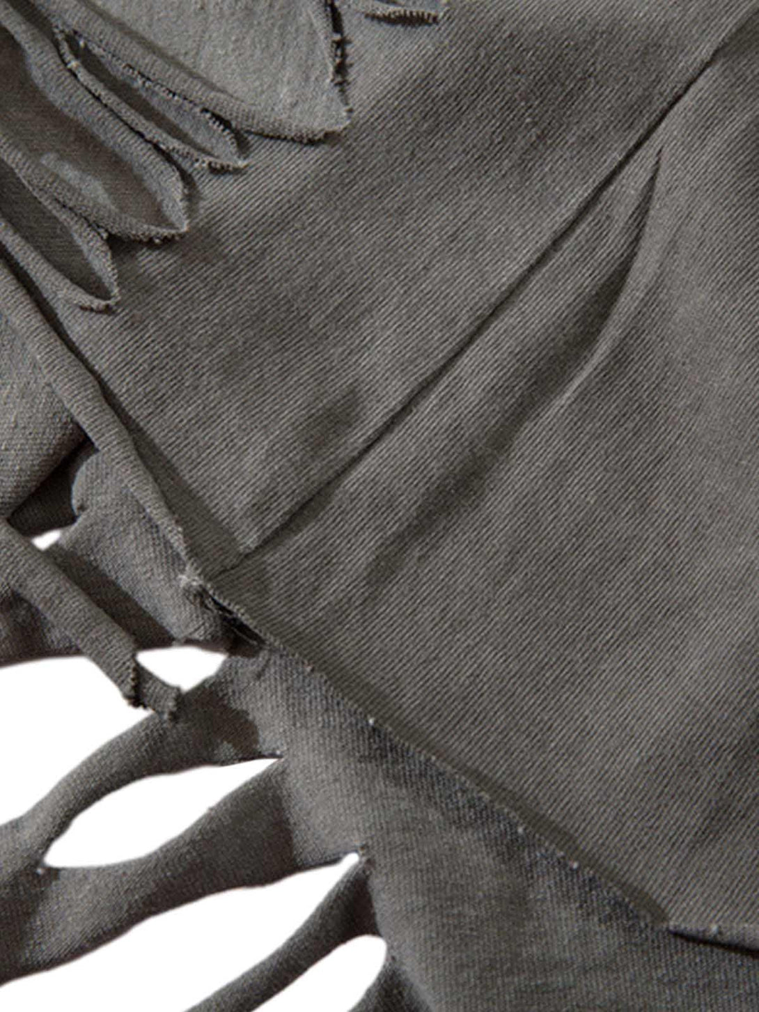 Zoomed-in texture of distressed fabric with ripped details on a vest by TALISHKO.