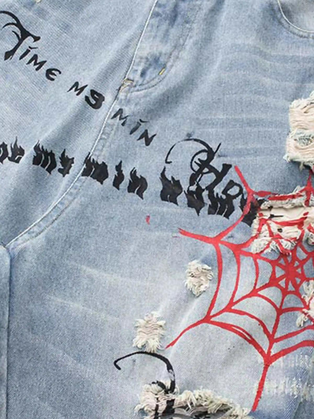 Intricate look at the distressed fabric and spider web print on TALISHKO jeans, showcasing unique design.