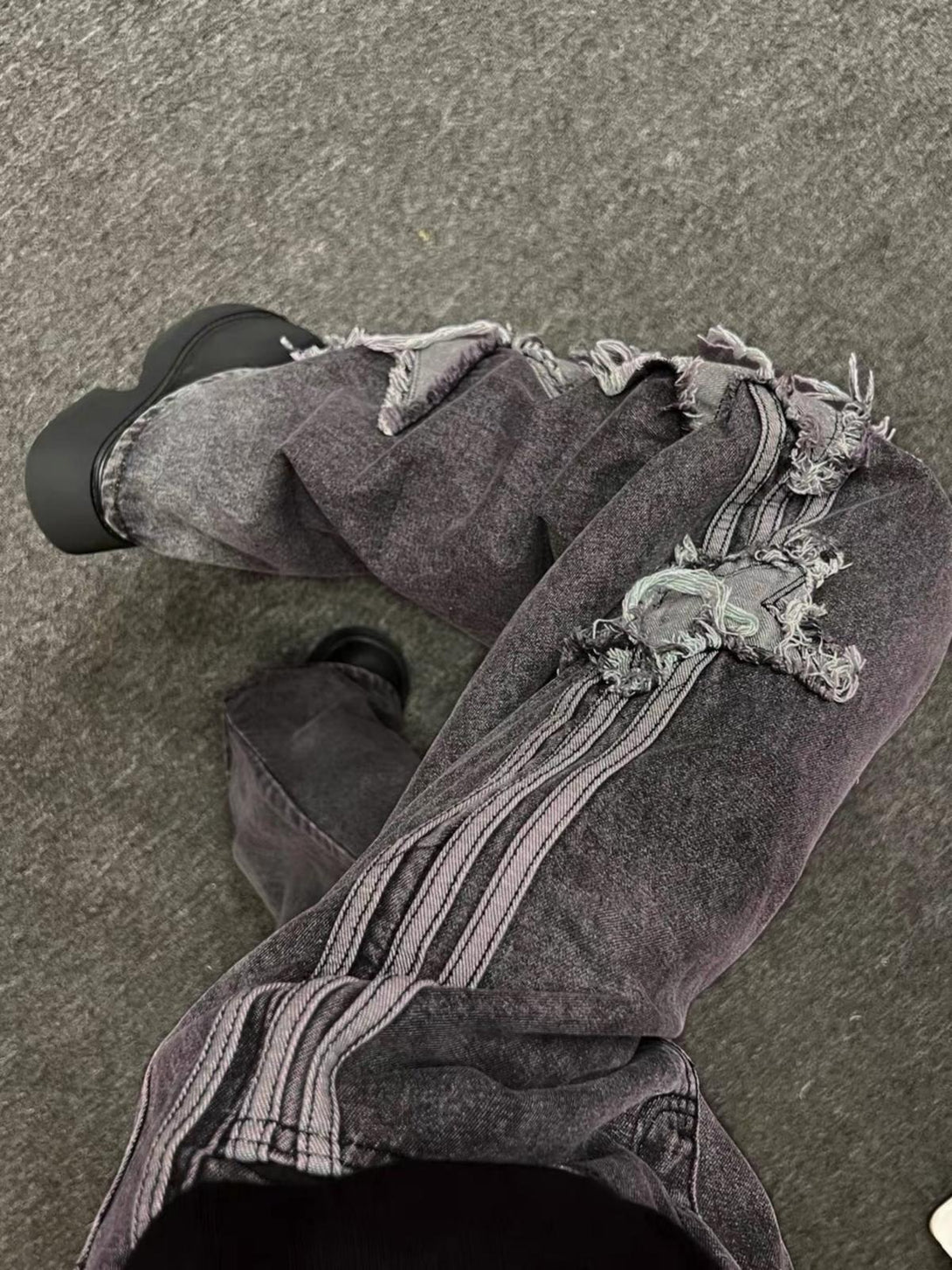 Intricate look at TALISHKO distressed jeans, highlighting frayed details and star patch design.