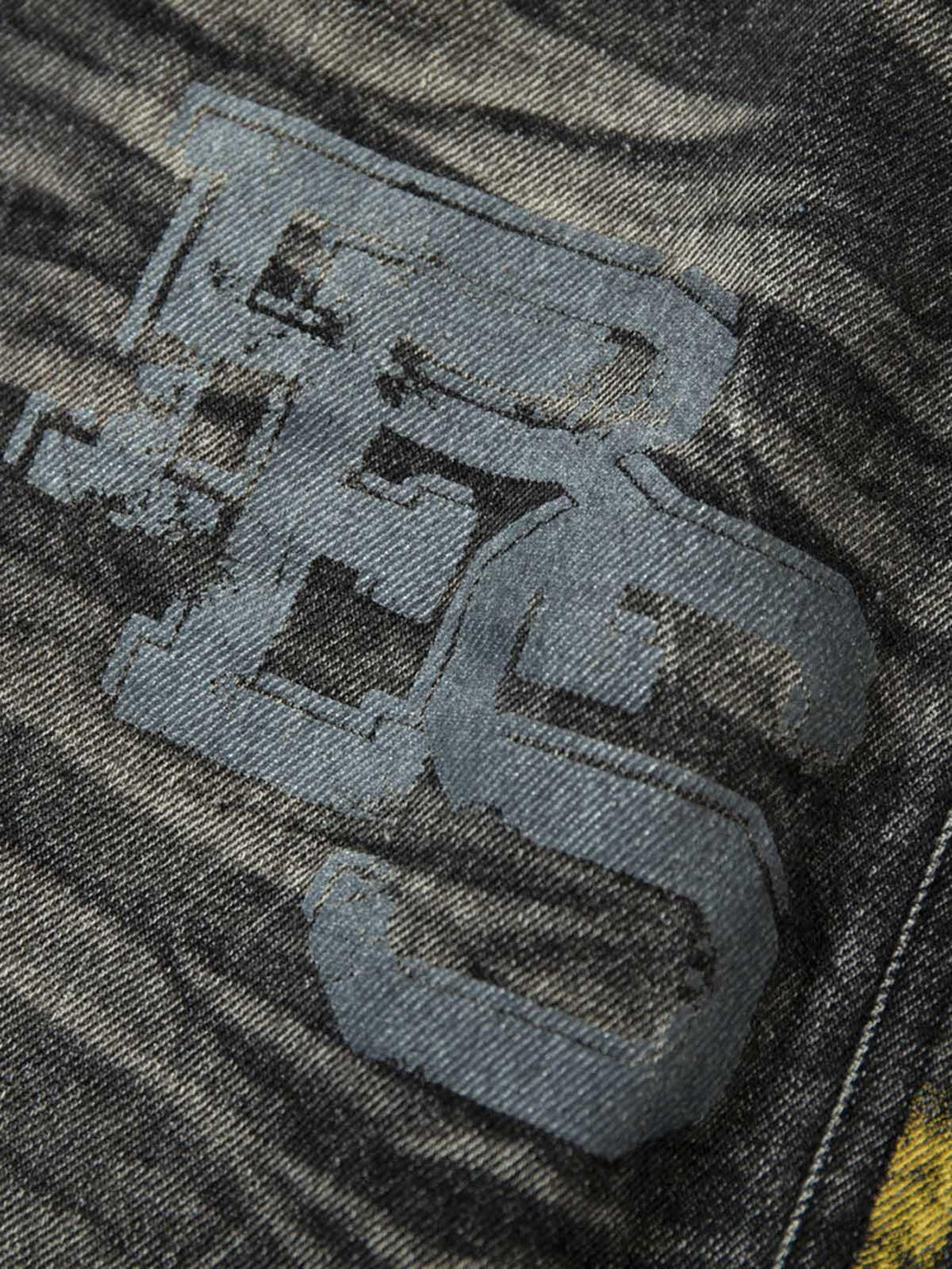 A detailed view of TALISHKO jeans featuring a distressed texture and bold patchwork design.