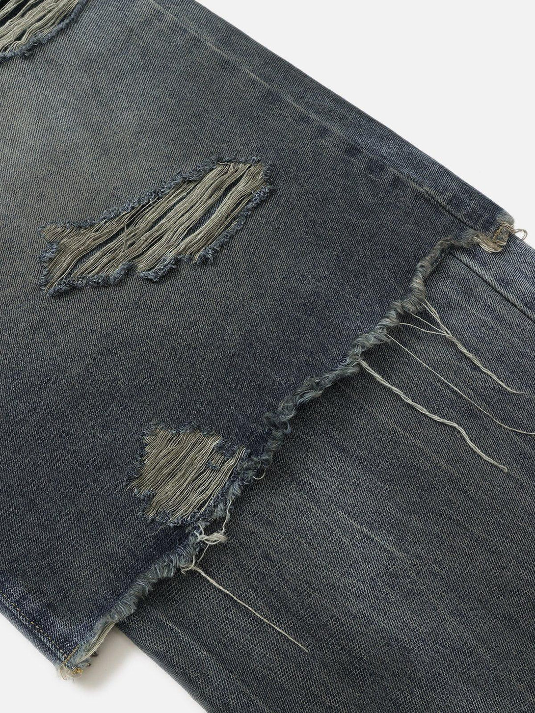 Frayed and distressed texture of TALISHKO's layered baggy jeans, showcasing unique design details.