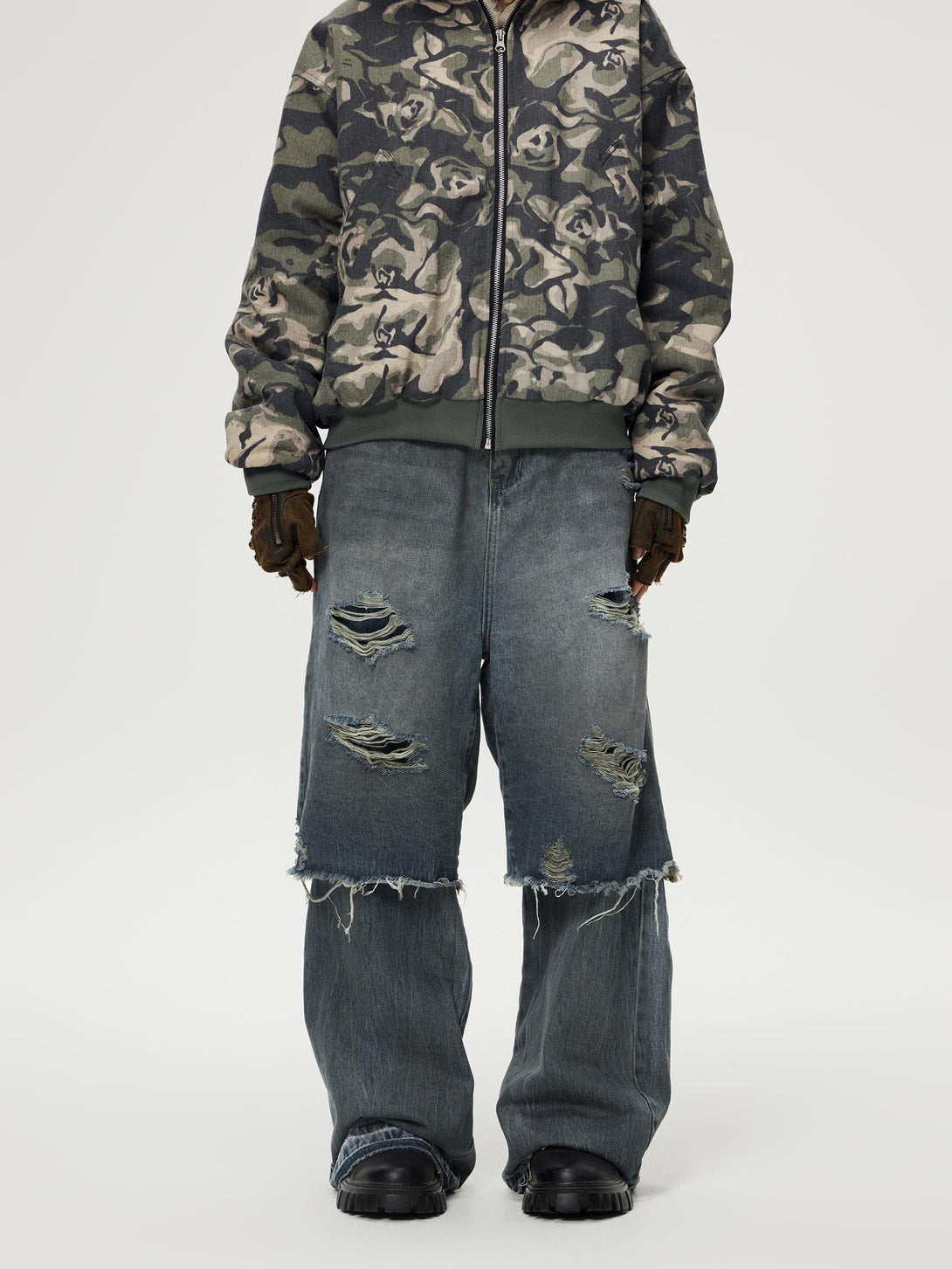 Model in TALISHKO camo jacket and ripped baggy jeans, embracing a rugged streetwear vibe.