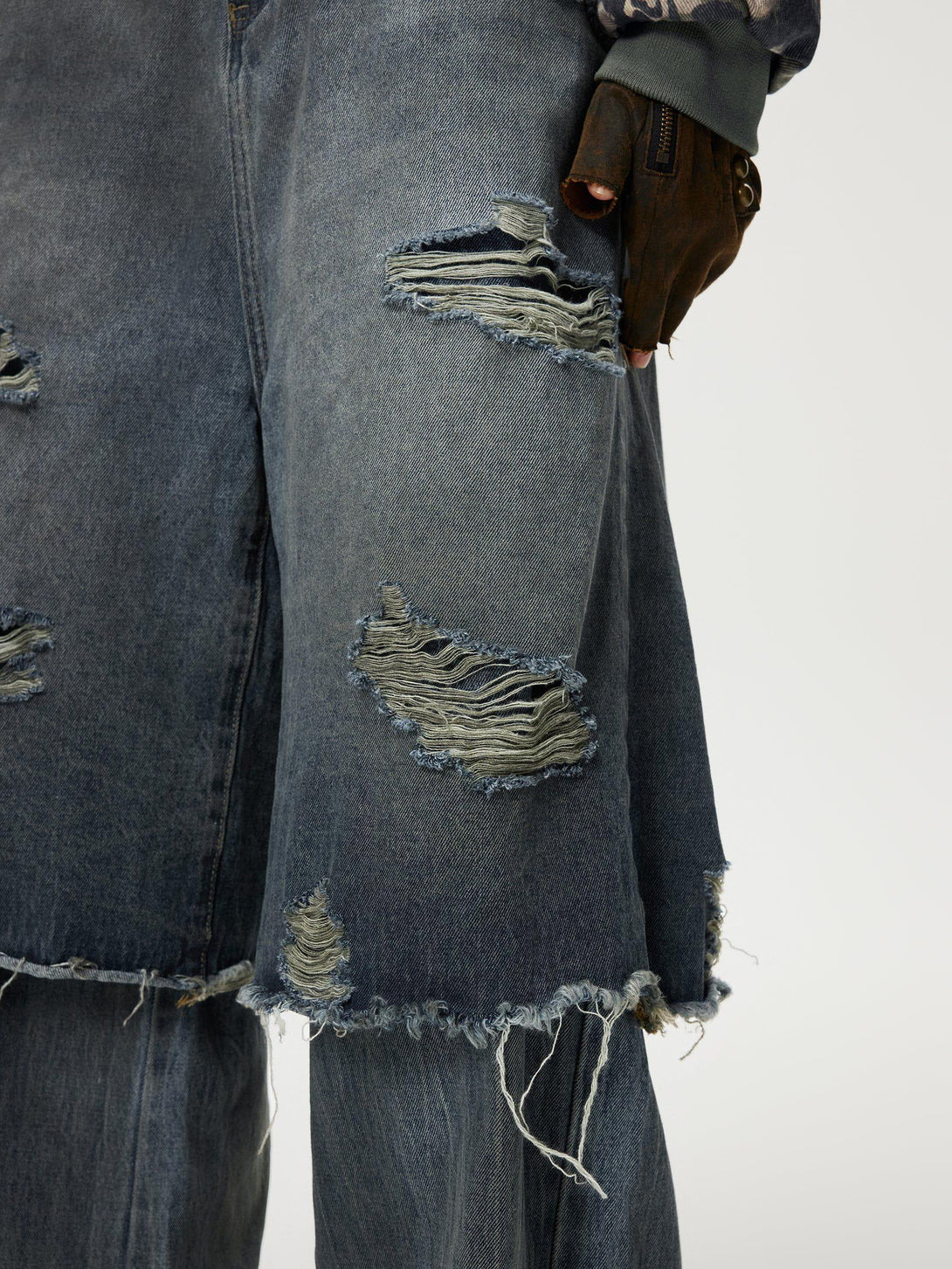 TALISHKO's distressed jeans with frayed edges and layered design, highlighting rugged style.