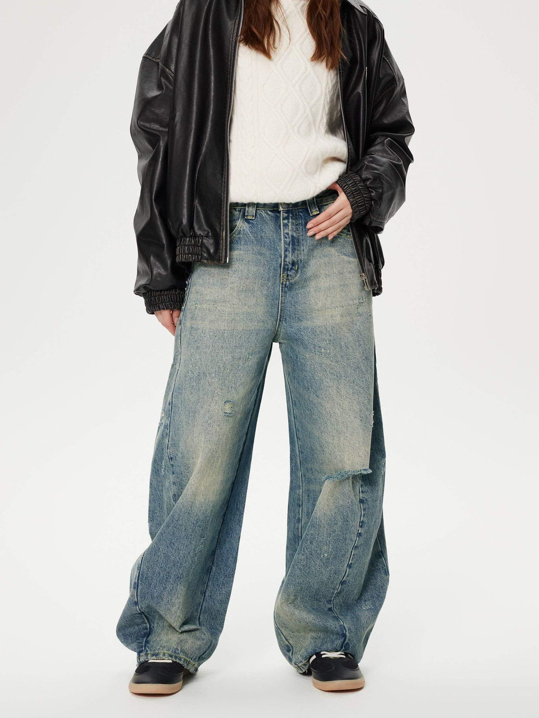 Model in TALISHKO distressed barrel jeans, styled with a cozy sweater and leather jacket.