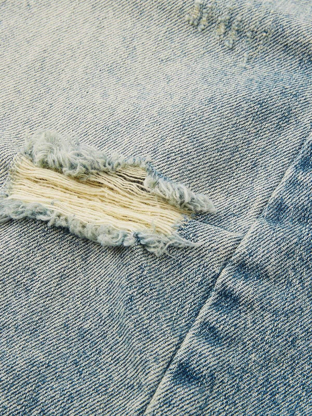 Intricate look at TALISHKO's distressed denim texture and frayed detailing.