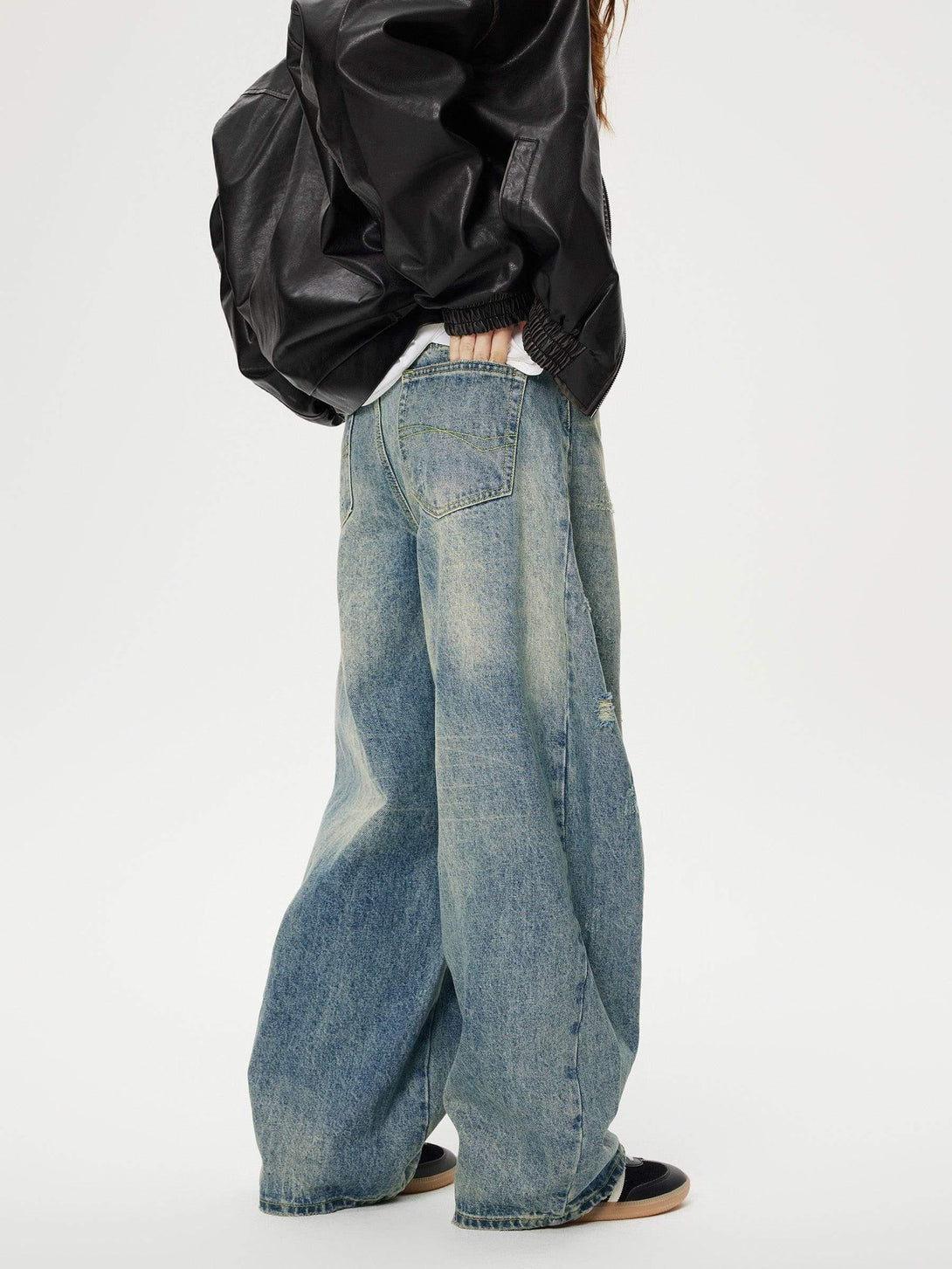 Model in TALISHKO distressed barrel jeans, paired with a black leather jacket for a bold look.