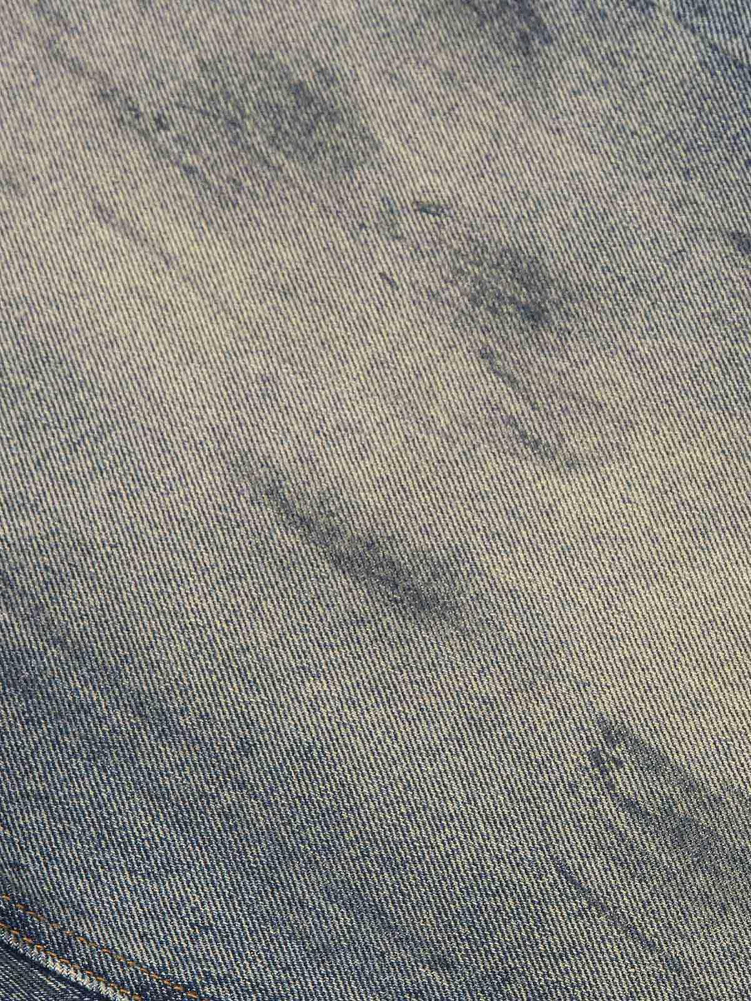 Focusing on the intricate texture of TALISHKO distressed jeans with a washed ink-splashed effect.