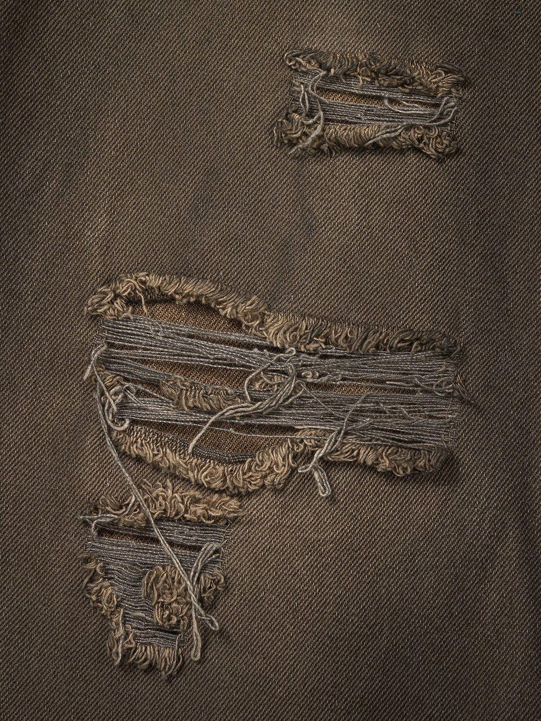 Intricate look at TALISHKO distressed washed jeans fabric, highlighting unique frayed details.