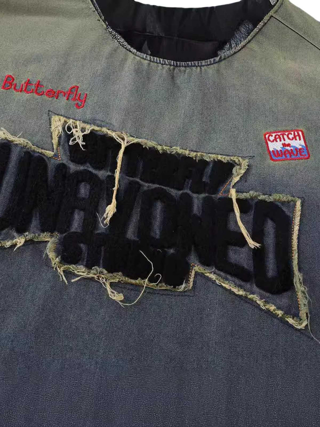 A detailed look at the distressed patchwork on a TALISHKO gradient denim T-shirt.