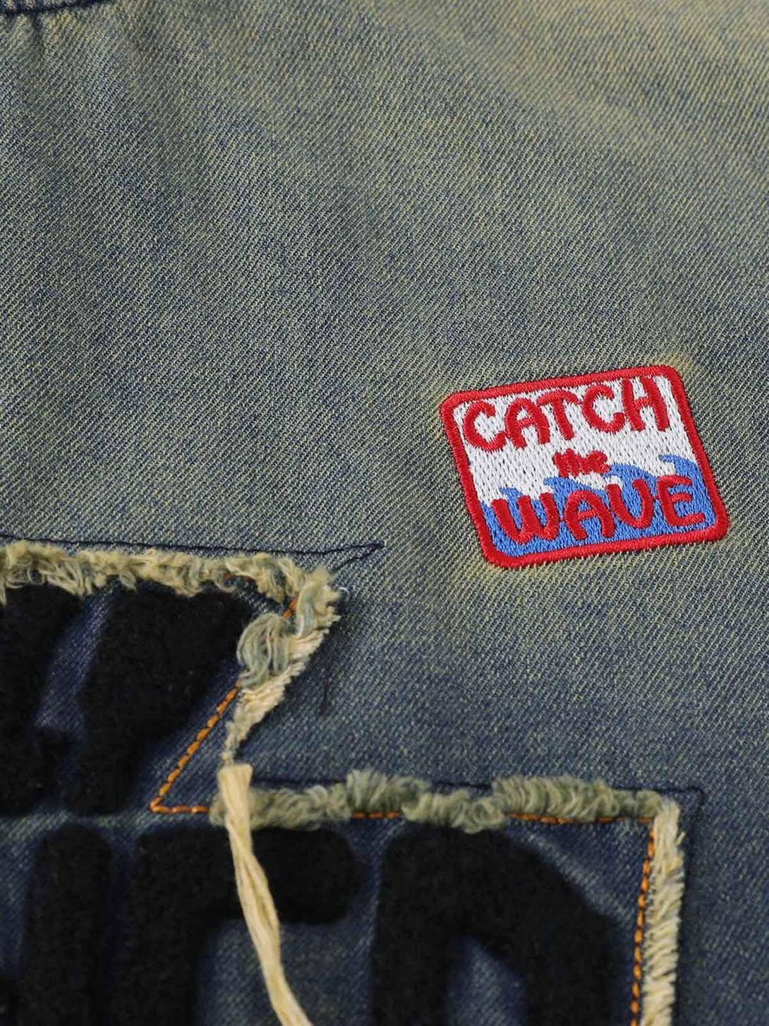 Zoomed-in view of a patch on TALISHKO's distressed denim T-shirt, adding a unique touch.