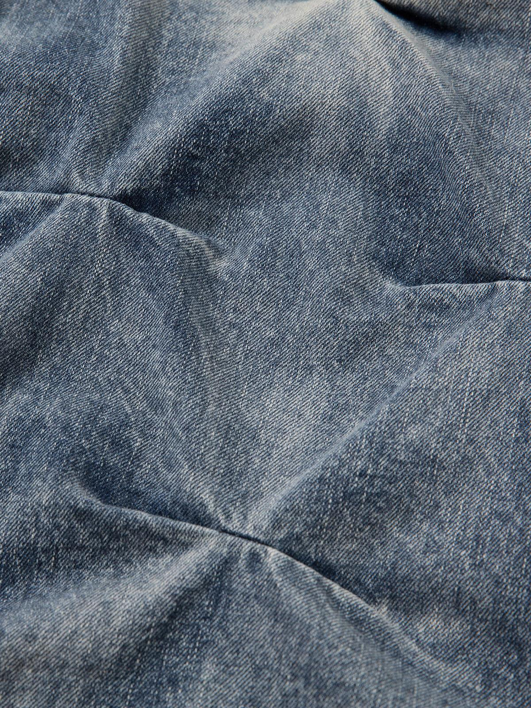 Zoomed-in texture of TALISHKO distressed washed pleated jeans, highlighting unique fabric detail.