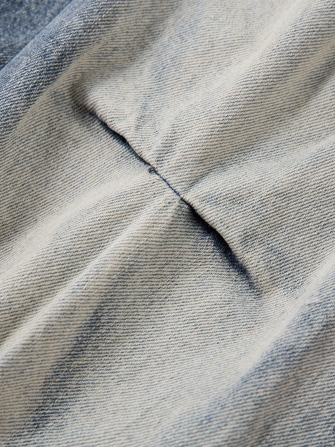 Intricate look at TALISHKO's distressed washed pleated jeans, showcasing unique fabric texture.