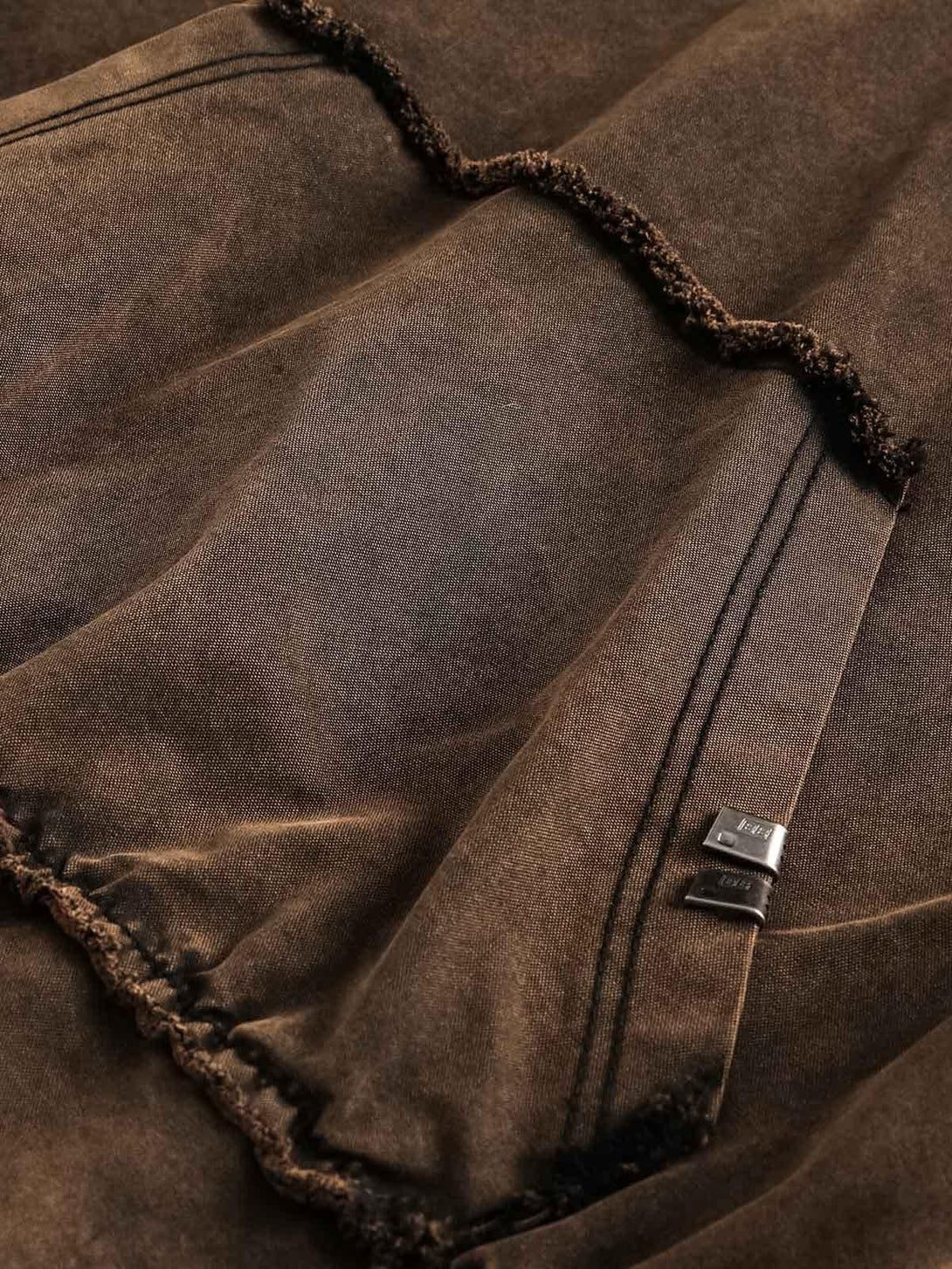 A close-up of TALISHKO's distressed denim sweatshirt, showcasing its textured fabric and stitching.