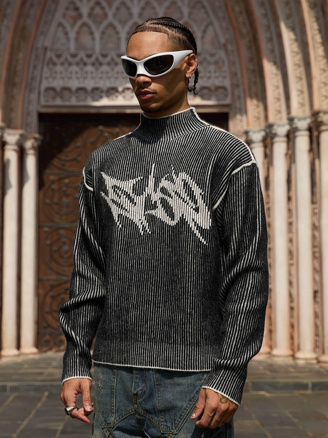 Model sporting a TALISHKO sweater with bold graphic design and white sunglasses, exuding urban flair.