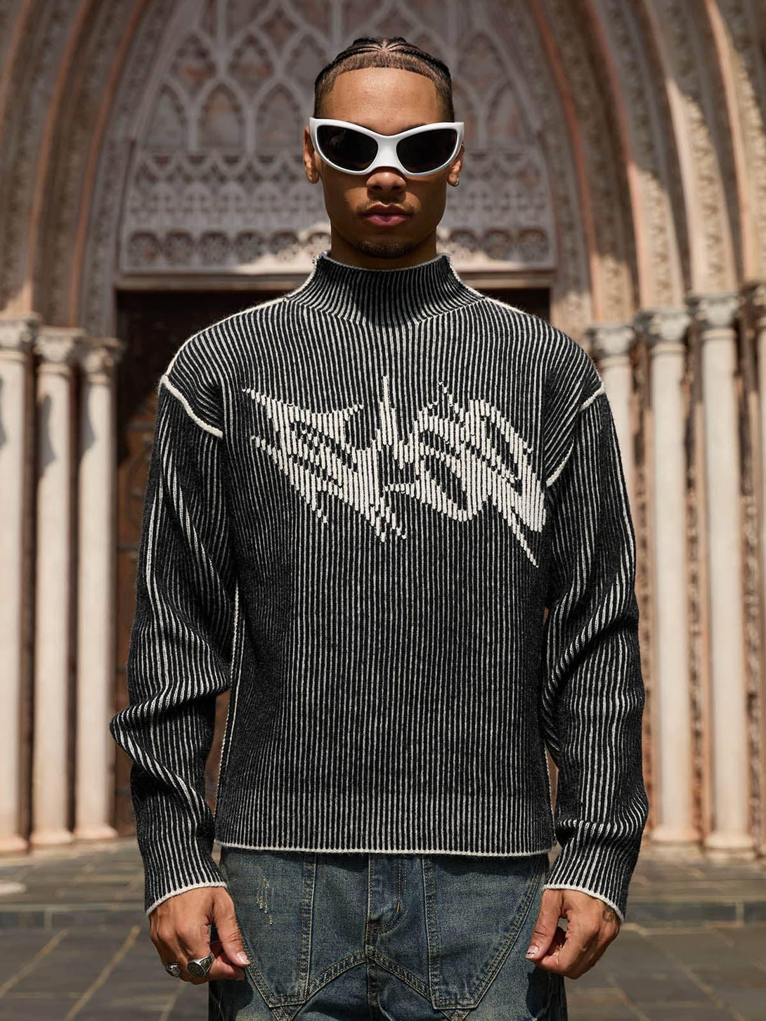 Model wearing a graphic TALISHKO sweater with white sunglasses, showcasing bold urban style.