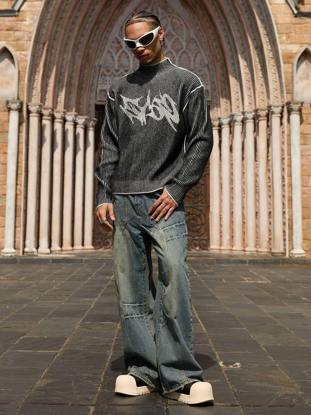 Model in TALISHKO's double-sided sweater with graphic design, paired with stylish white sunglasses.