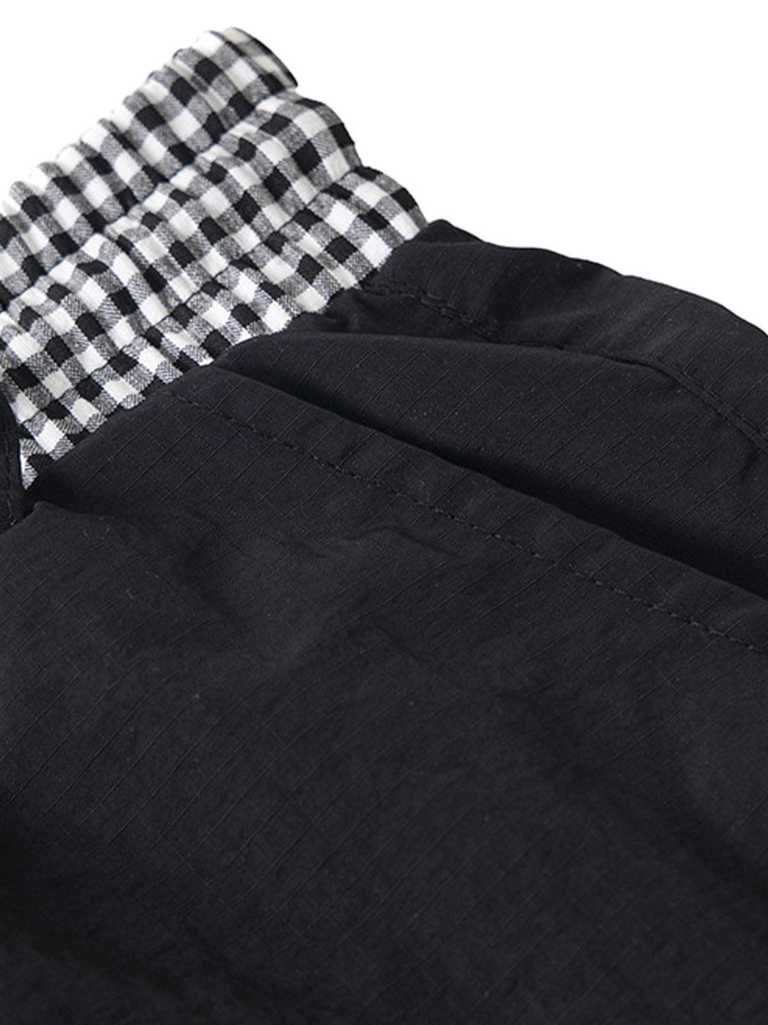 Detailed fabric and stitching of black baggy cargo pants, featuring a double waist design by TALISHKO.