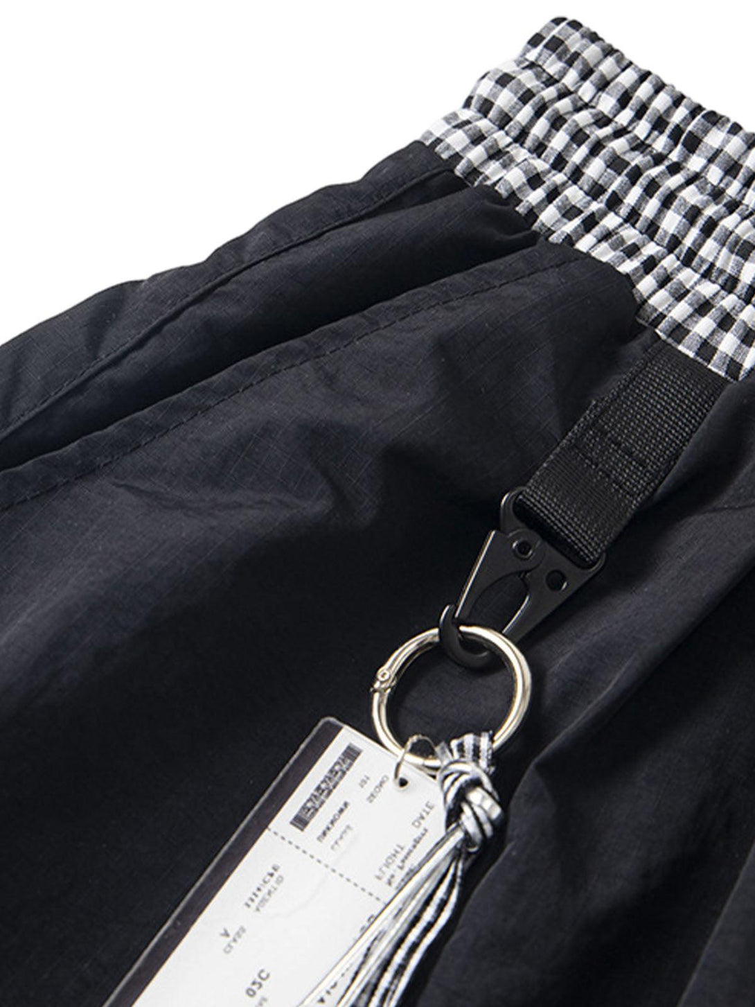 A detailed view of the drawstring and keychain detail on TALISHKO's baggy cargo pants.