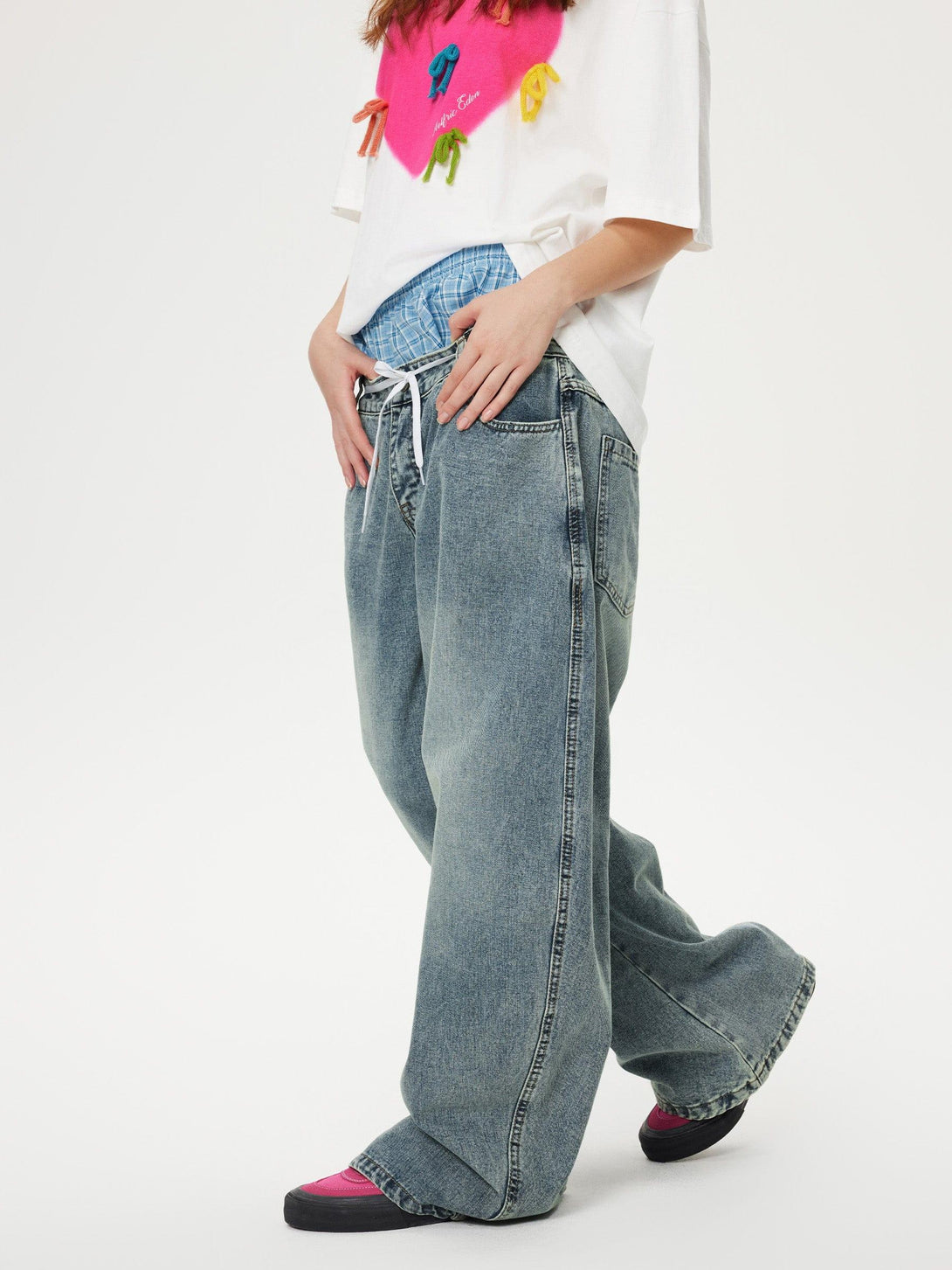 Model in TALISHKO double waist loose jeans, styled with a colorful graphic tee and layered waistband.