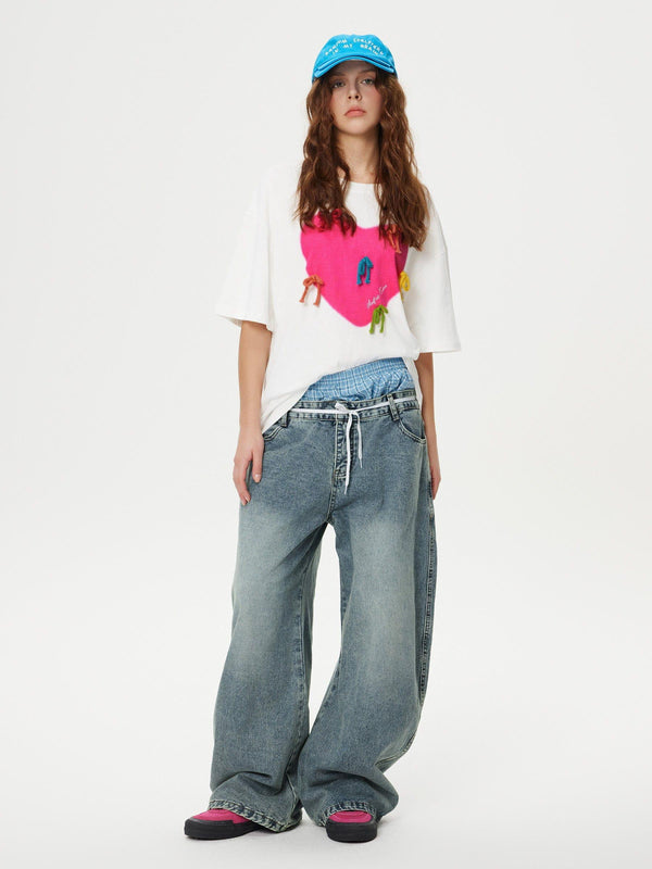 Model wearing TALISHKO double waist loose sagging jeans paired with a vibrant graphic tee.