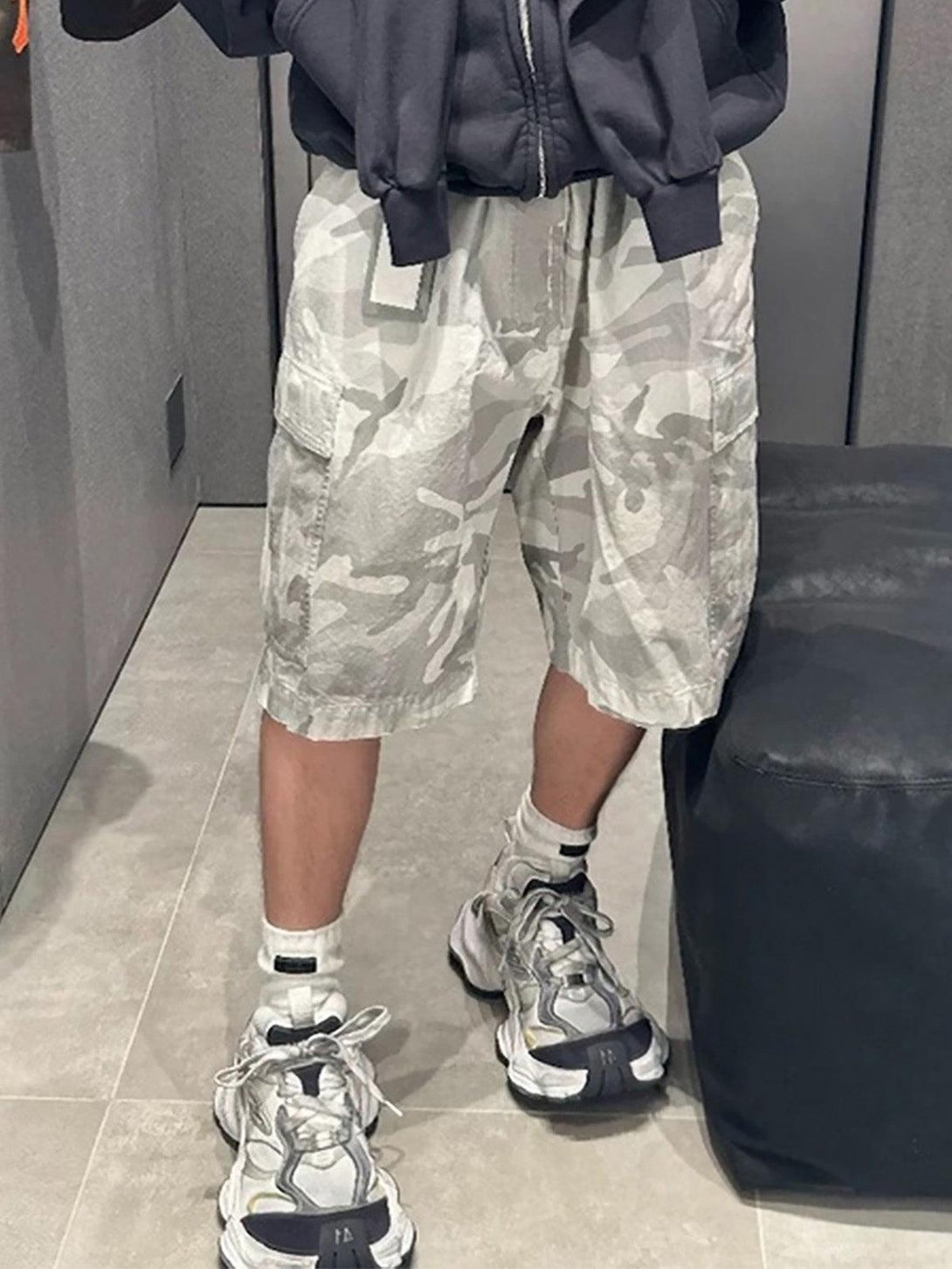 TALISHKO camouflage cargo shorts styled on a model, highlighting a relaxed and trendy look.