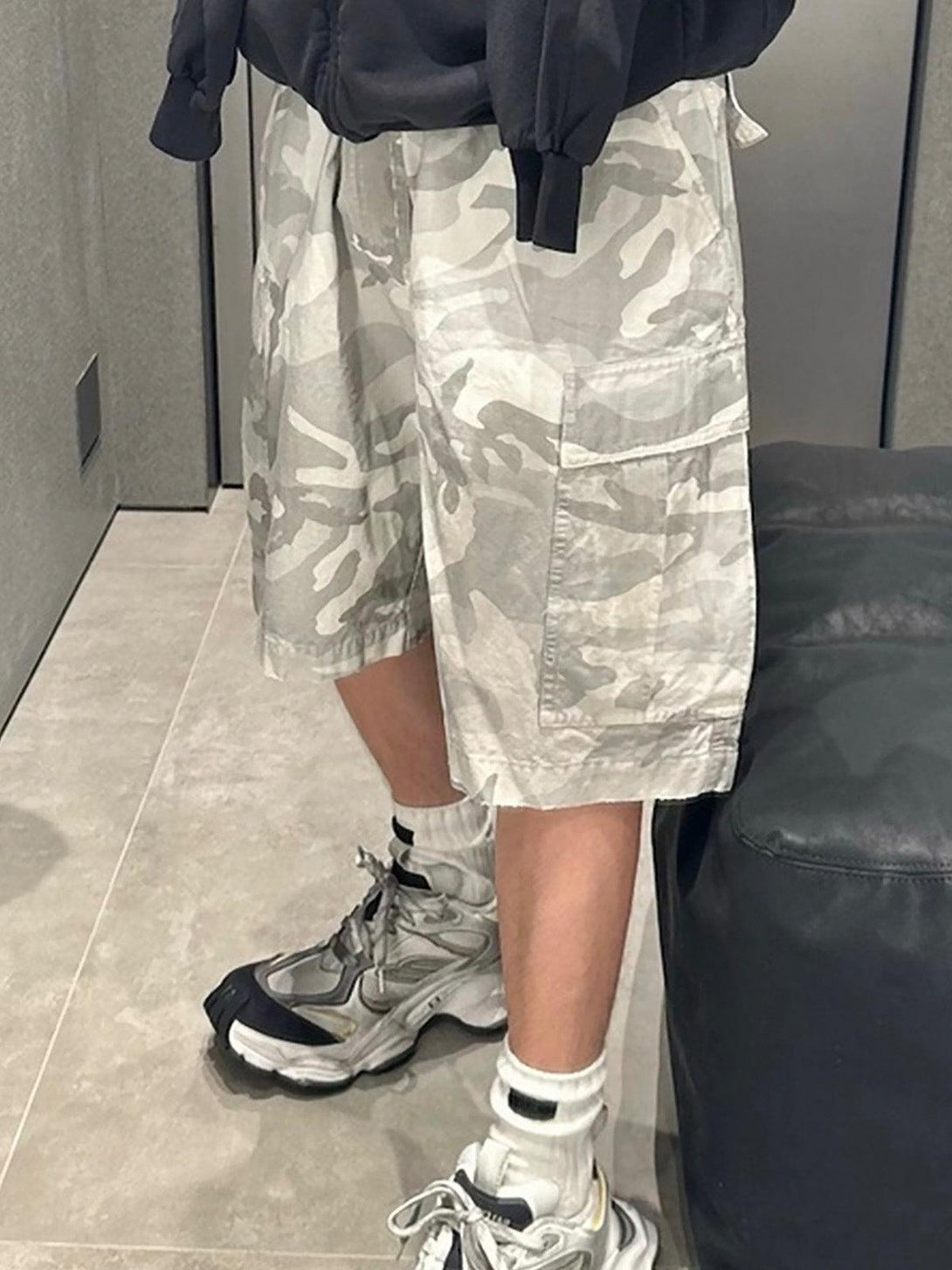 Model wearing TALISHKO drawstring camouflage cargo shorts paired with sneakers for a relaxed look.