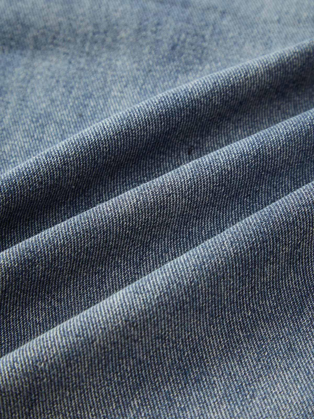 Zoomed-in texture of TALISHKO denim fabric, highlighting the washed finish and weave detail.