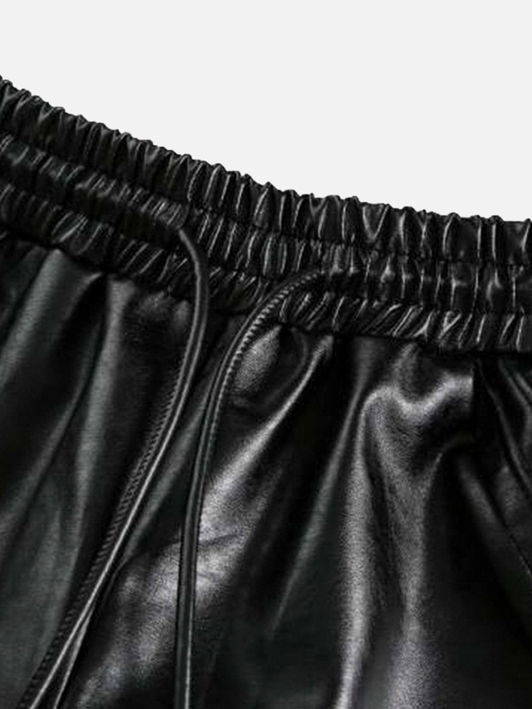 Focusing on the sleek faux leather texture of TALISHKO's drawstring shorts, perfect for a stylish look.
