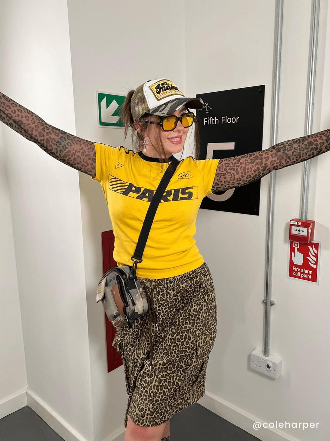 Model in leopard print skirt with a bright yellow top and camo hat, styled by TALISHKO.