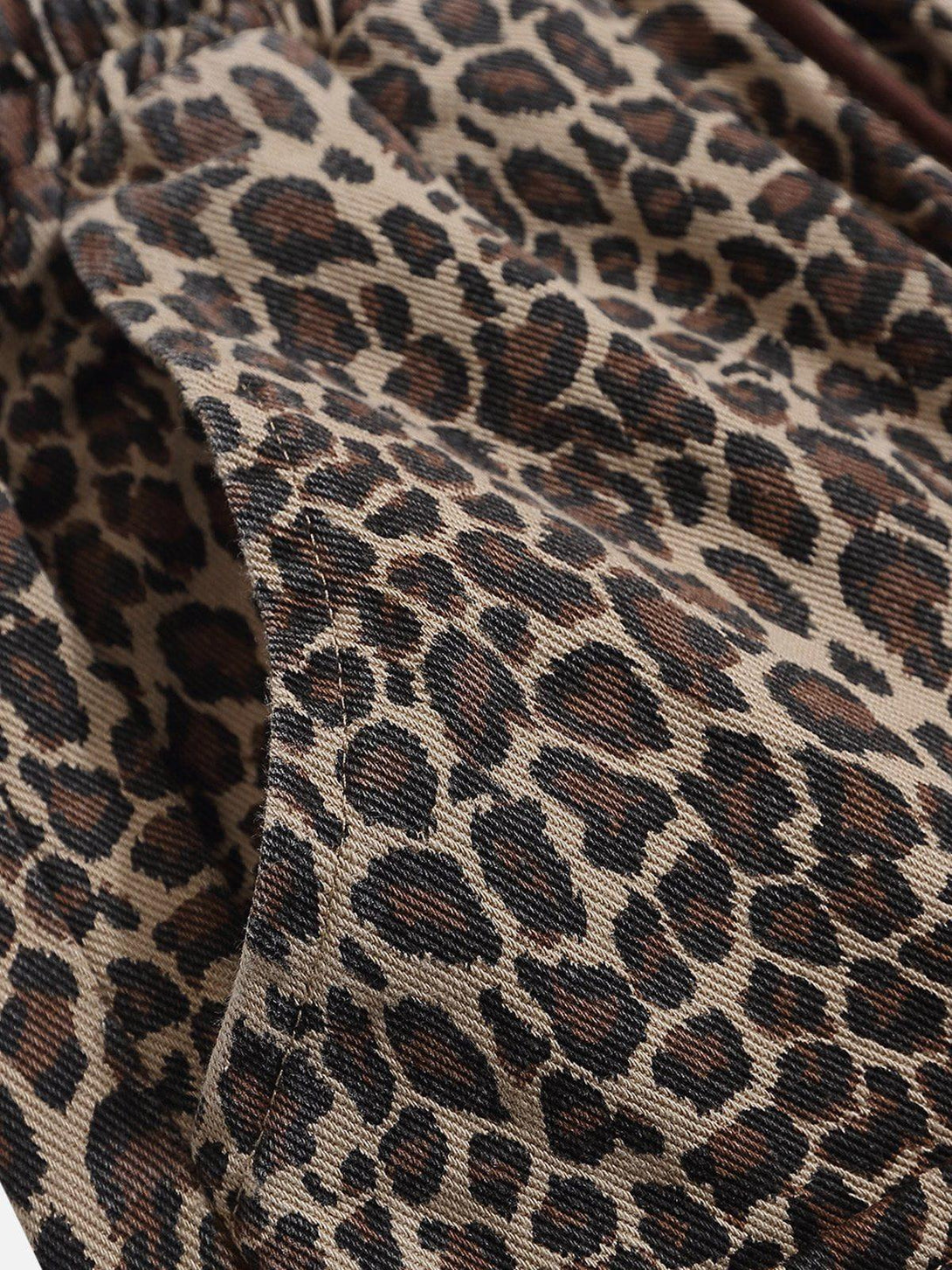 Zoomed-in texture of leopard print shorts by TALISHKO, highlighting detailed fabric pattern.