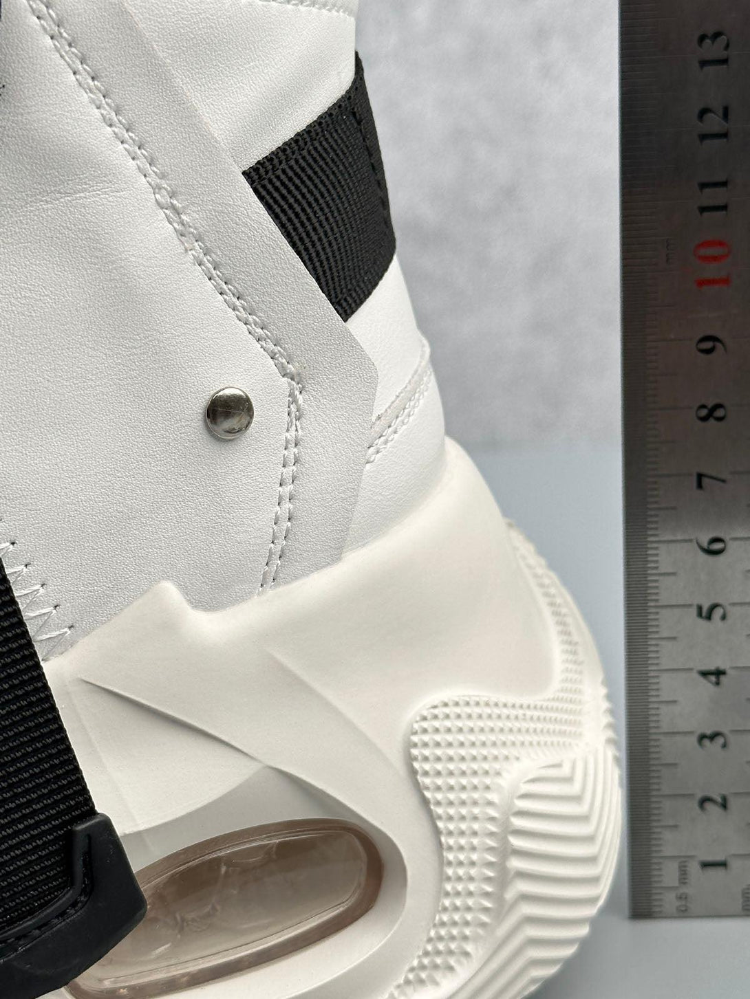Close-up of white TALISHKO runner boots, highlighting the unique sole design and texture.