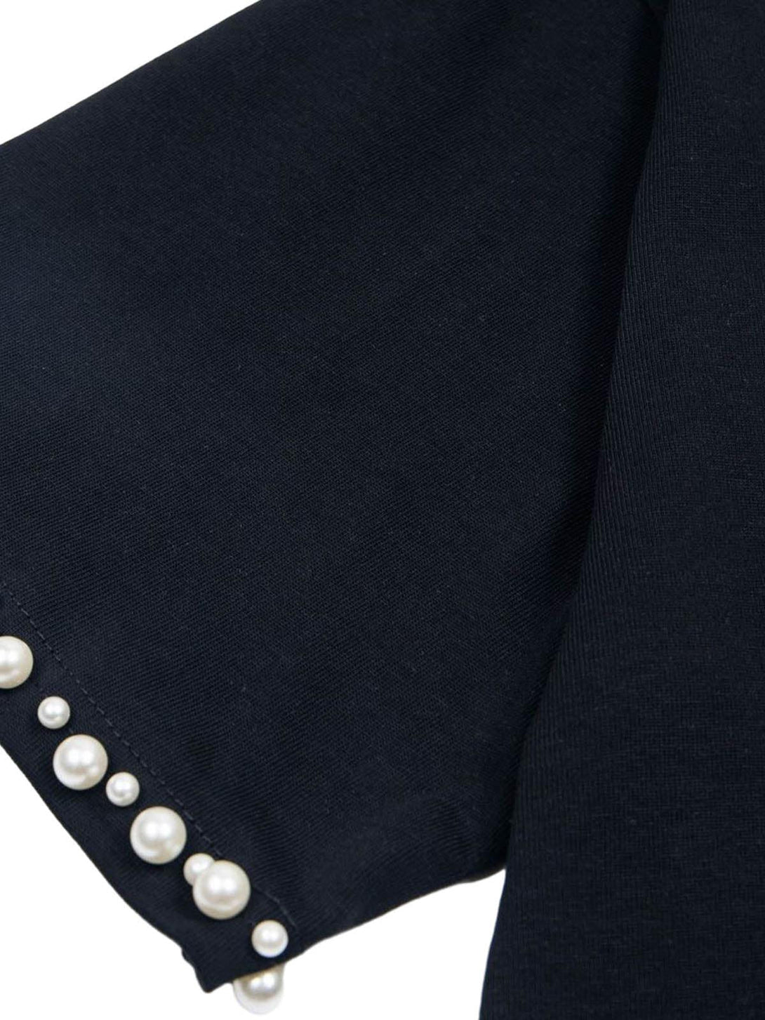 Intricate view of pearl accents on TALISHKO's black T-shirt sleeve, adding an elegant touch.