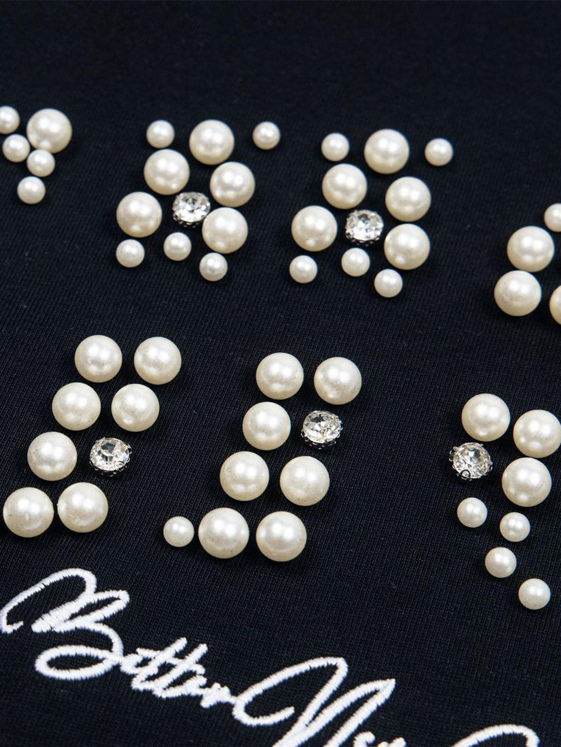 Pearl and gem details on black fabric from TALISHKO's elegant oversized T-shirt collection.