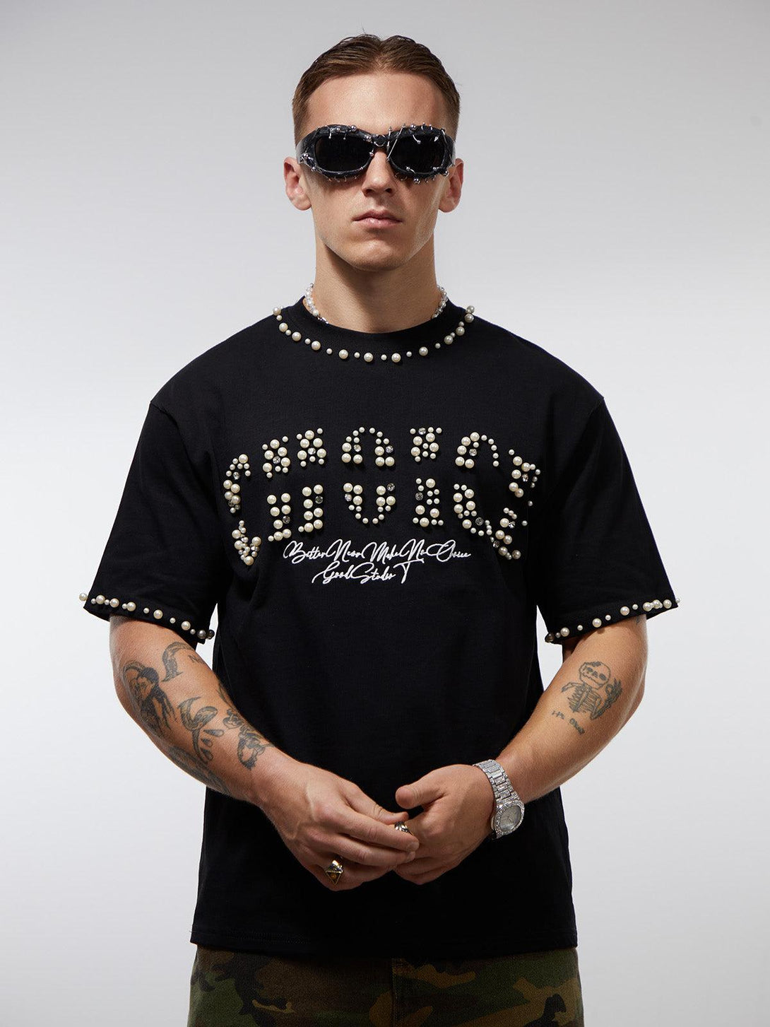 Model wearing a black pearl-embellished oversized T-shirt by TALISHKO, paired with sunglasses.