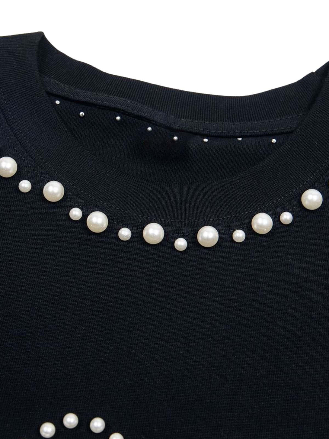 Pearl accents on the neckline of a black oversized T-shirt by TALISHKO, showcasing chic details.