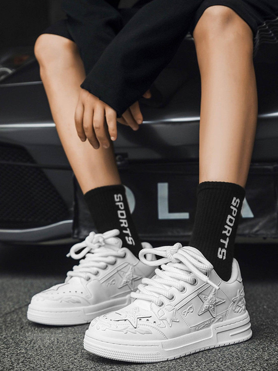 A stylish pair of white embossed star board shoes by TALISHKO, paired with sporty black socks.