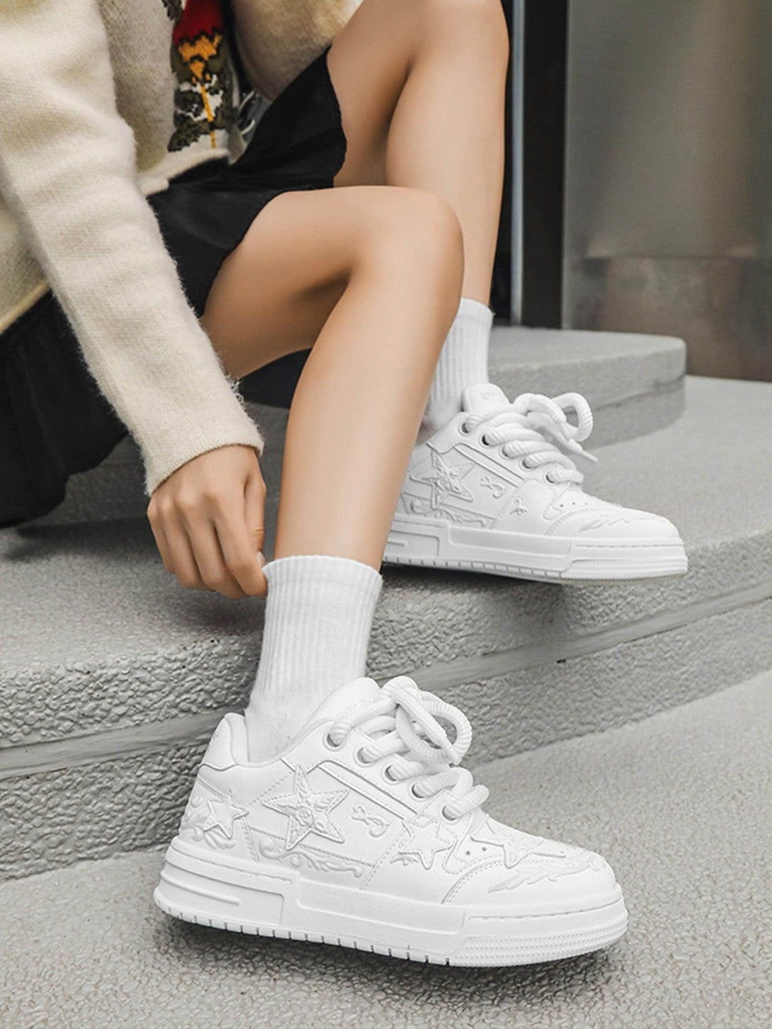 TALISHKO's white embossed stars board shoes paired with a cozy sweater for a chic look.