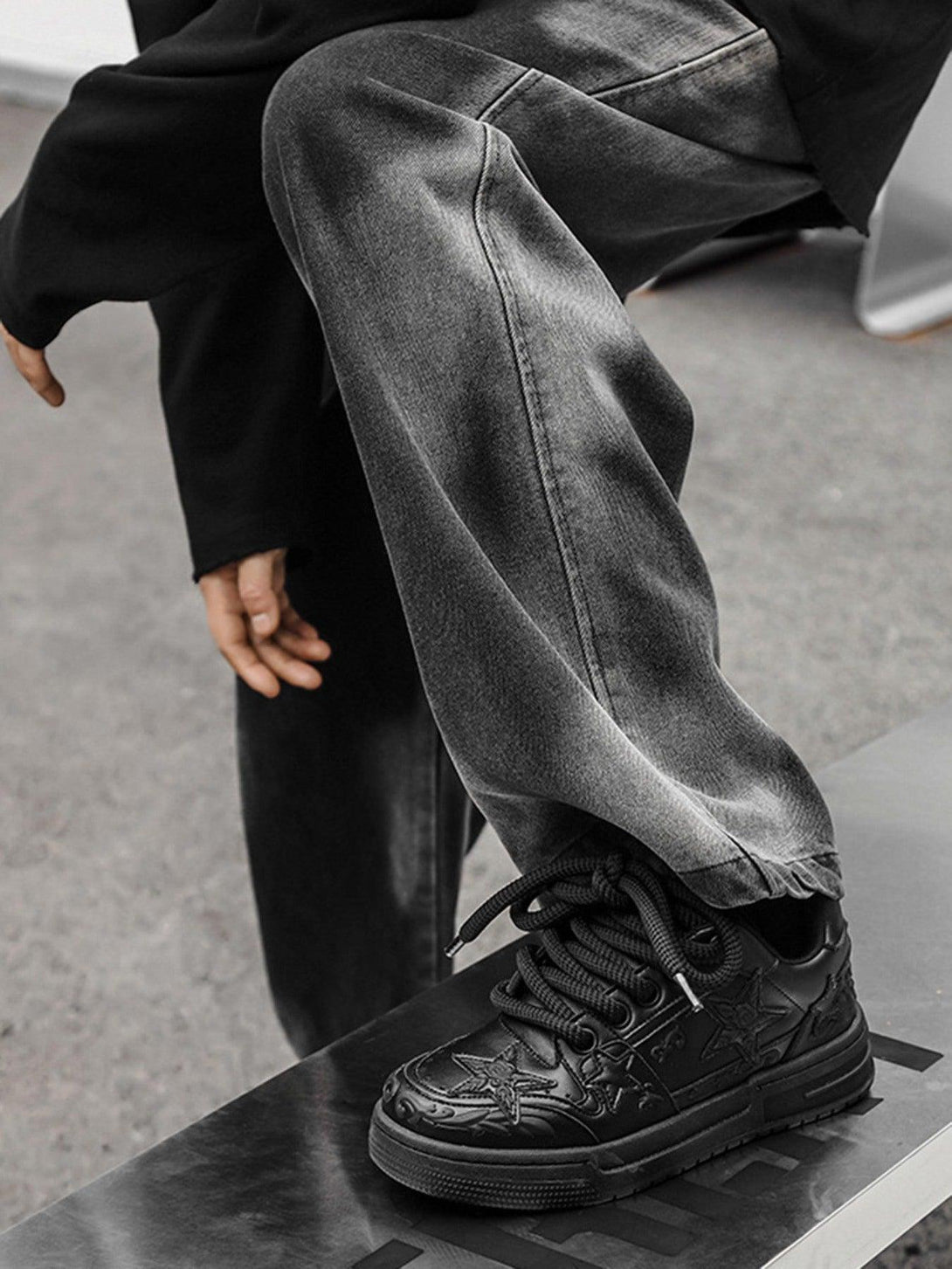 TALISHKO's black casual board shoes with embossed stars, paired with dark jeans for a sleek look.