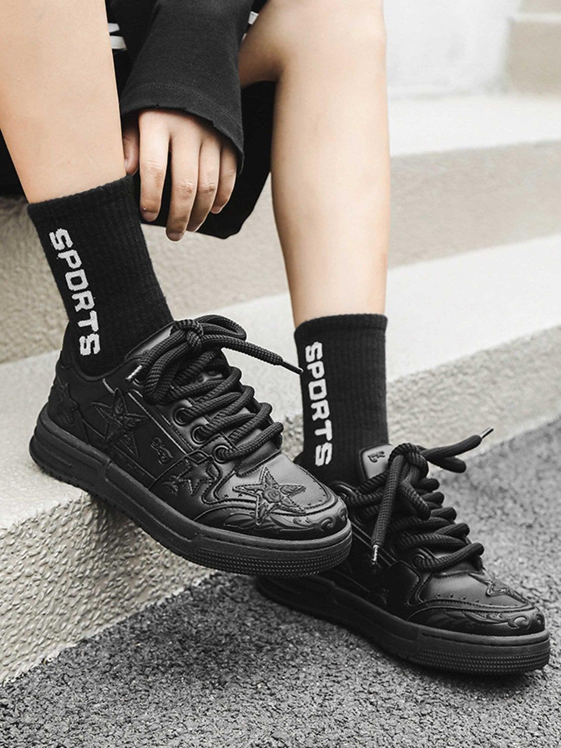 TALISHKO's embossed star board shoes in black, paired with sporty socks for a trendy look.
